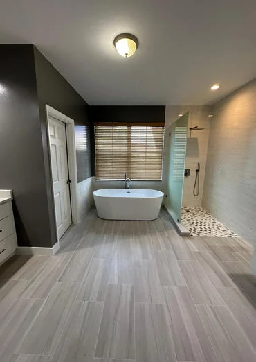 Bathroom after renovation, with clean neutral flooring and a modern freestanding tub