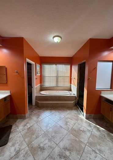 Bathroom before renovation, with warm orange walls and a traditional tub