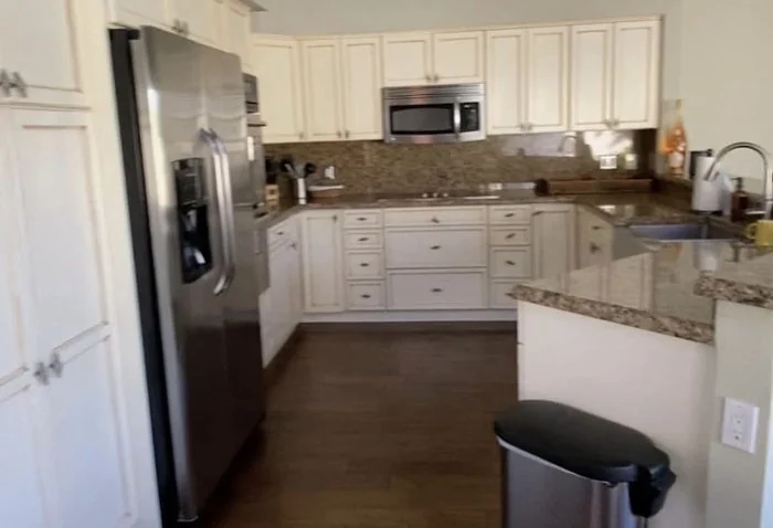 Kitchen before refresh, with existing cabinets, appliances and a dark floor